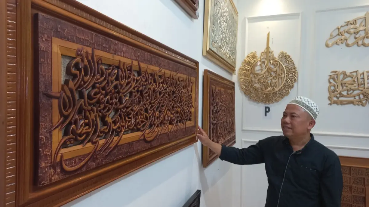 MENAWAN: Norhadi menunjukkan karya kaligrafi di gerai rumah usahanya. (FIKRI THOHARUDIN/RADAR KUDUS)