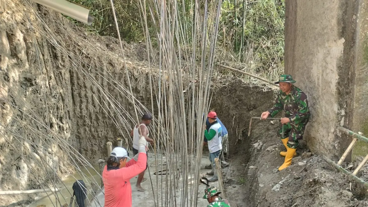 SEMANGAT: Warga Desa Jati bersama Personel Koramil 11/Jati, Kodim 0721/Blora, membangun pondasi jembatan. 