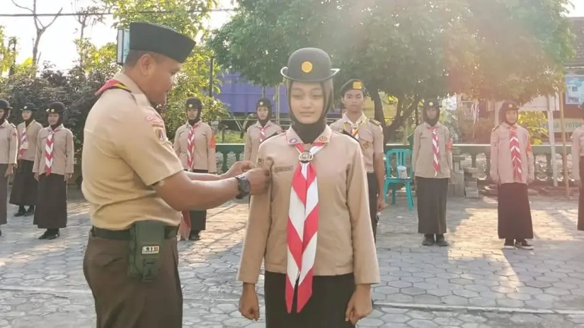 DISEMATKAN: Pamong Saka Koptu Eko Pramono saat menyemangatkan atribut ke anggota Saka Wira Kartika.