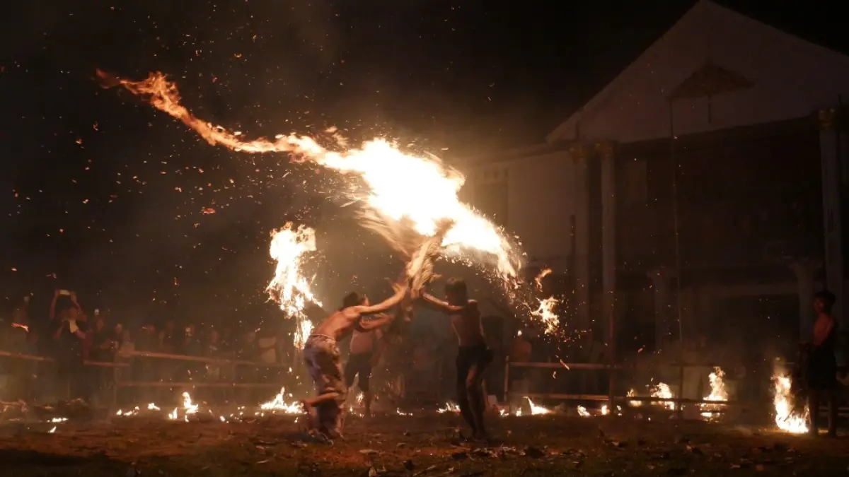 EKSTREM: Para pemain perang api dari pelepah kelapa melakukan atraksi budaya, dengan mengantamkan obor satu satu lain.
