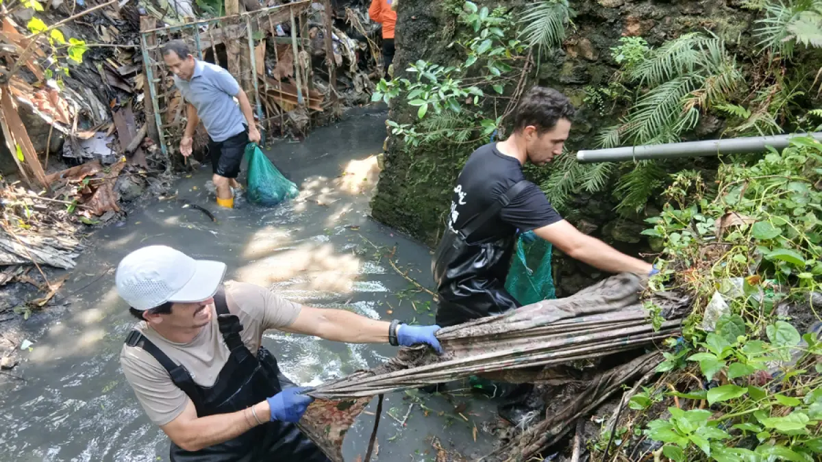 BERSIH SUNGAI: Sam (bertopi) dan Gary (kanan) berusaha mencabut sampah kain lebar yang tetanam di tepi sungai. Sedangkan Direktur Jawa Pos Radar Kudus Baehaqi (belakang) membawa karung berisi sampah yang dipungut di Sungai Bacin. (EKO SANTOSO/RADAR KUDUS)