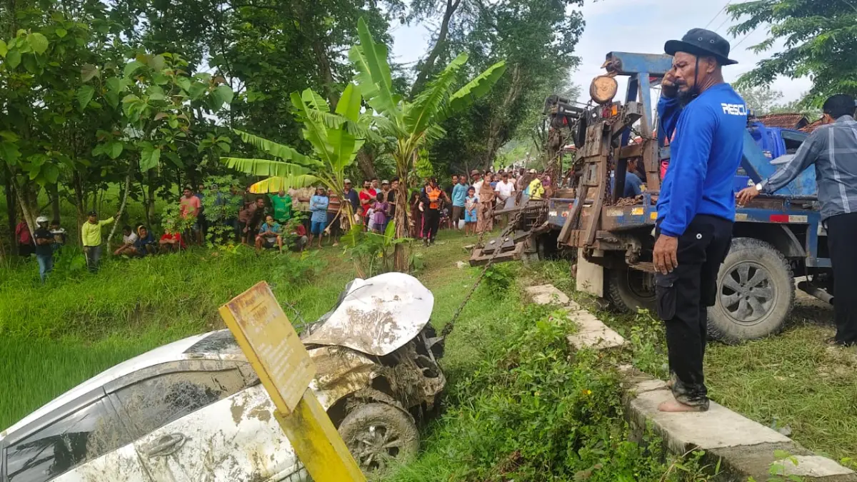 EVAKUASI – Mobil Avanza putih korban kecelakaan KAI sedang dievakuasi menggunakan truk derek untuk mengangkat mobil dari sawah ke jalan di perlintasan tanpa palang di Desa Sidorejo, Kecamatan Pulokulon. 