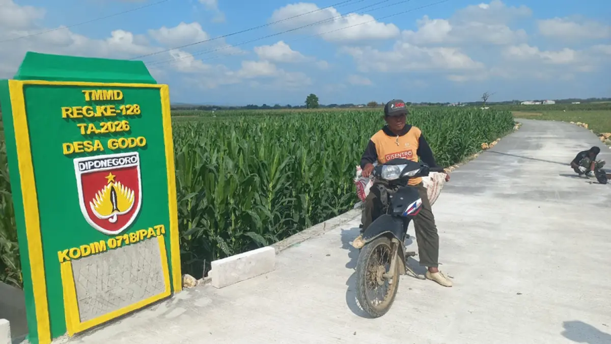 Salah seorang petani melintas di jalan beton yang dibangun oleh Satgas TMMD Reguler ke-128 Kodim 0718/Pati bersama masyarakat. (ACHMAD ULIL ALBAB/RADAR KUDUS)