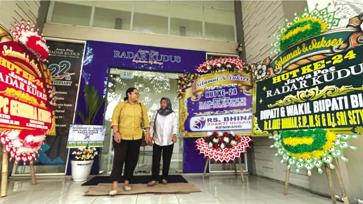 DARI BERBAGAI INSTANSI: Karyawan Jawa Pos Radar Kudus Septa dan Ulky melewati&nbsp;karangan bunga ucapan HUT ke-24 Radar Kudus di pintu masuk Radar Kudus Building kemarin. (M. ULIN NUHA/RADAR KUDUS)