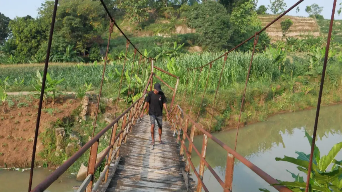 RAWAN: Warga Dukuh Toplek sedang melewati jembatan di Dukuh Pendem Desa Sumbberrejo Kecamatan Donorojo, Jepara, yang berbatasan dengan Dukuh Nglendoh, Desa Wedusan, Kecamatan Dukuhseti, Pati, yang rusak akibat banjir pada awal tahun lalu. (FIKRI THOHARUDIN/RADAR KUDUS)&nbsp;