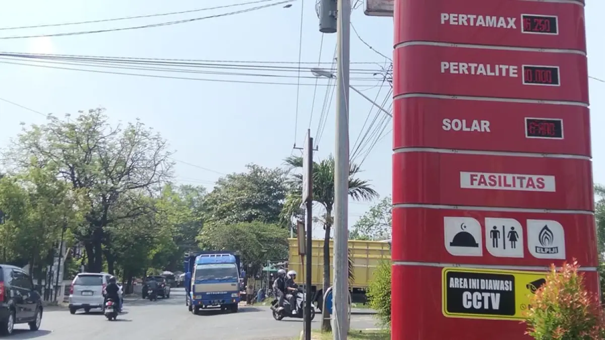 LEWAT: Pengguna jalan melintasi papan harga BBM di SPBU Gajahmati kemarin.  (ANDRE FAIDHIL FALAH/RADAR KUDUS)