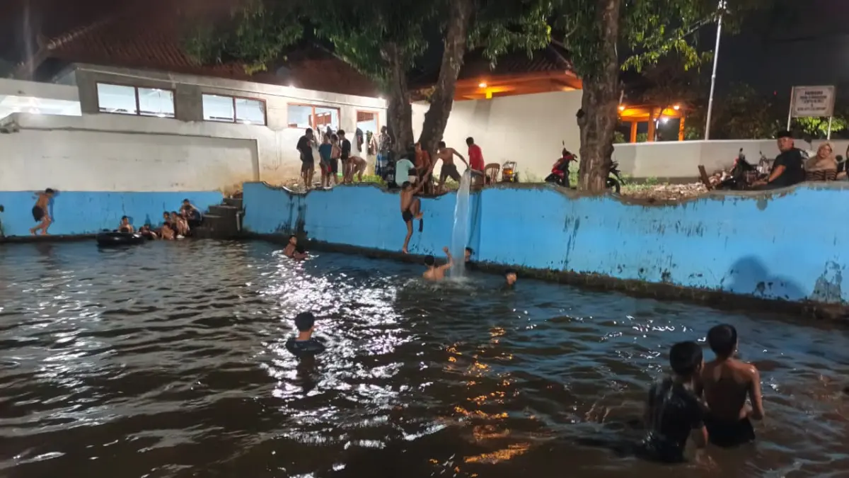 Anak - anak dan orang dewasa tampak asyik berenang di kolam yang berada di belakang makam Syekh Ahmad Mutamakin Kajen Pati. (ACHMAD ULIL ALBAB/RADAR KUDUS)