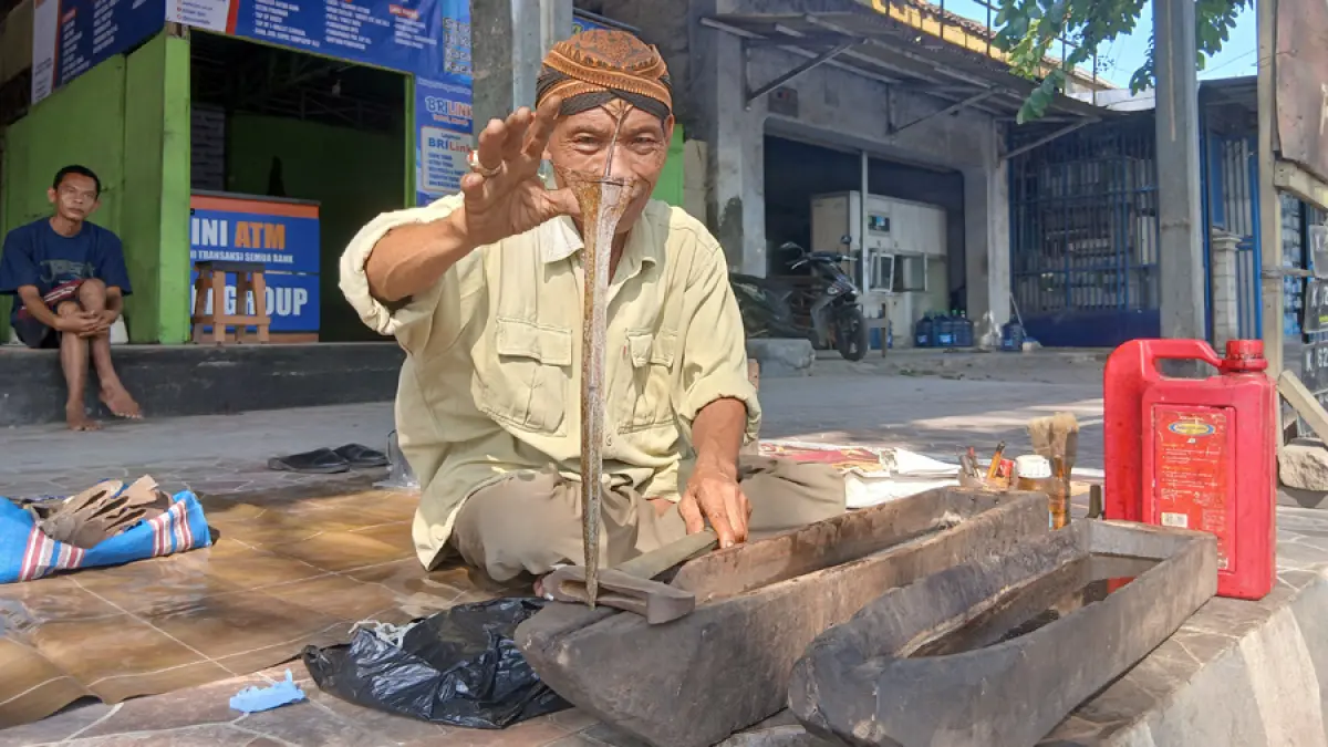 KEBUDAYAAN: Mulyono, saat menjamas keris di area eks Stasiun depan Blok T. (EKO SANTOSO/RADAR KUDUS)