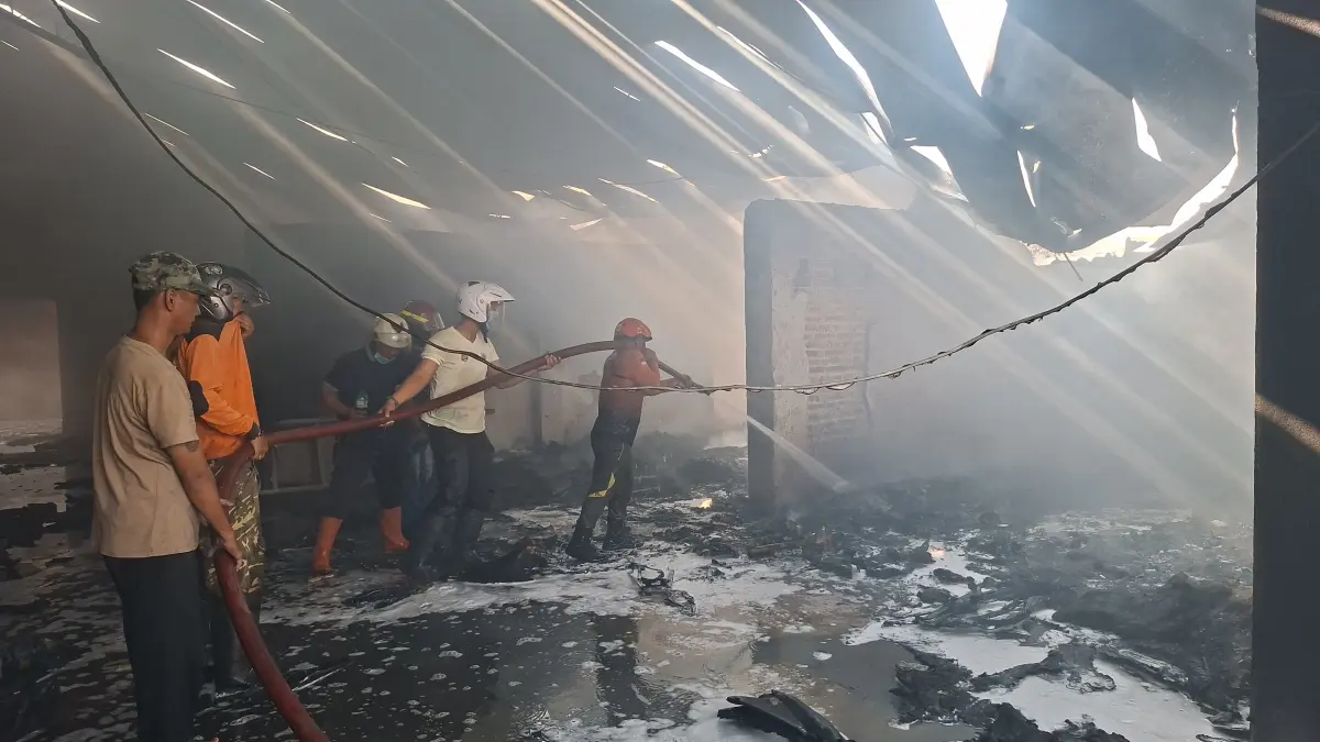 PADAMKAN: Petugas Damkar gabungan memadamkan api yang membakar gudang penyimpanan sparepart motor di Desa Getaspejaten, Minggu (5/7). (ANDIKA TRISNA SAPUTRA/RADAR KUDUS)