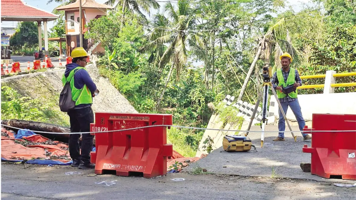 UKUR: Petugas pembangunan jalan mengukur titik-titik yang nantinya akan dipasang tiang penyangga dengan menggunakan alat teodolit di jalan depan portal masuk wisata Colo, Rabu (8/7). (ANDIKA TRISNA SAPUTRA/RADAR KUDUS)