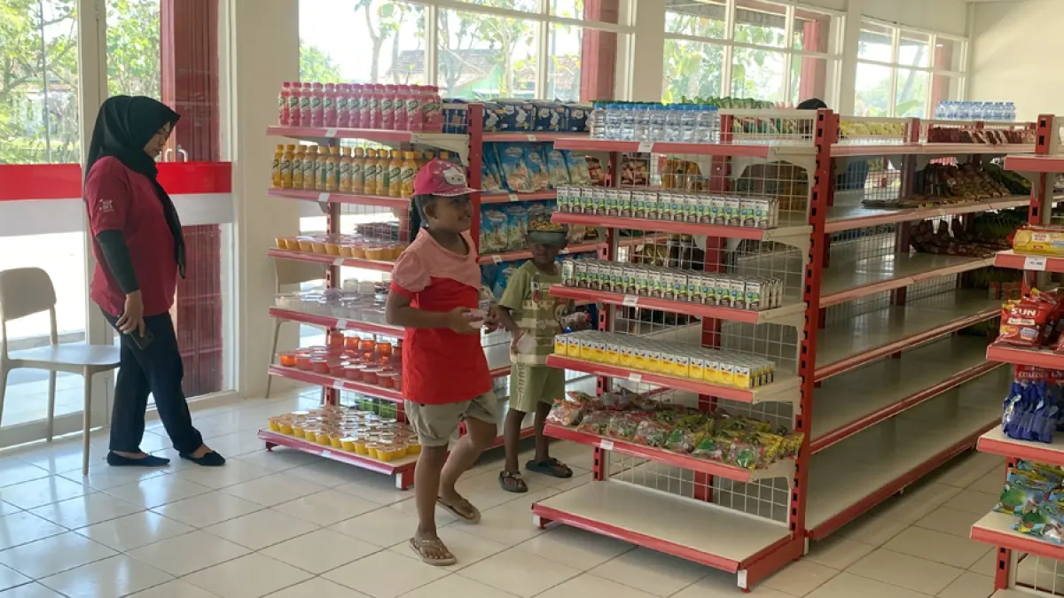 JUAL BELI: Suasana KDMP Desa Jejeruk saat ada pembeli dengan kedua anak. (ARIF FAKHRIAN KHALIM/RADAR KUDUS)