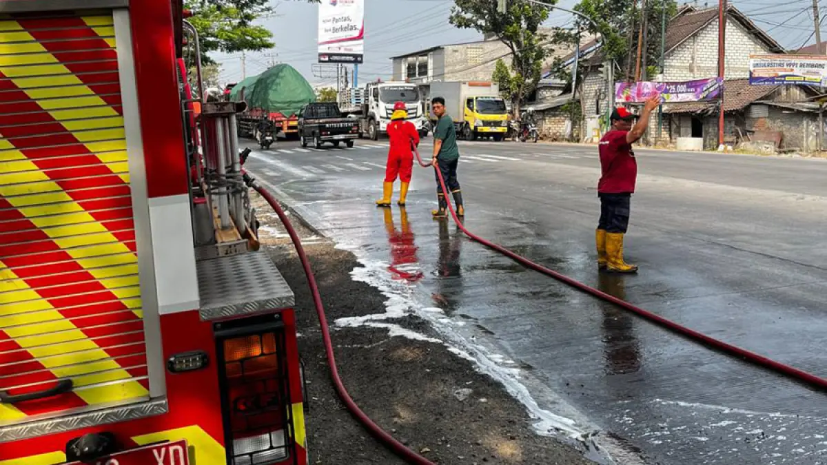 LICIN: Petugas Damkar Rembang melakukan pembersihan sisa cairan limbah dari campuran tepung ikan di jalan pantura Rembang kemarin sore. (DAMKAR UNTUK RADAR KUDUS)