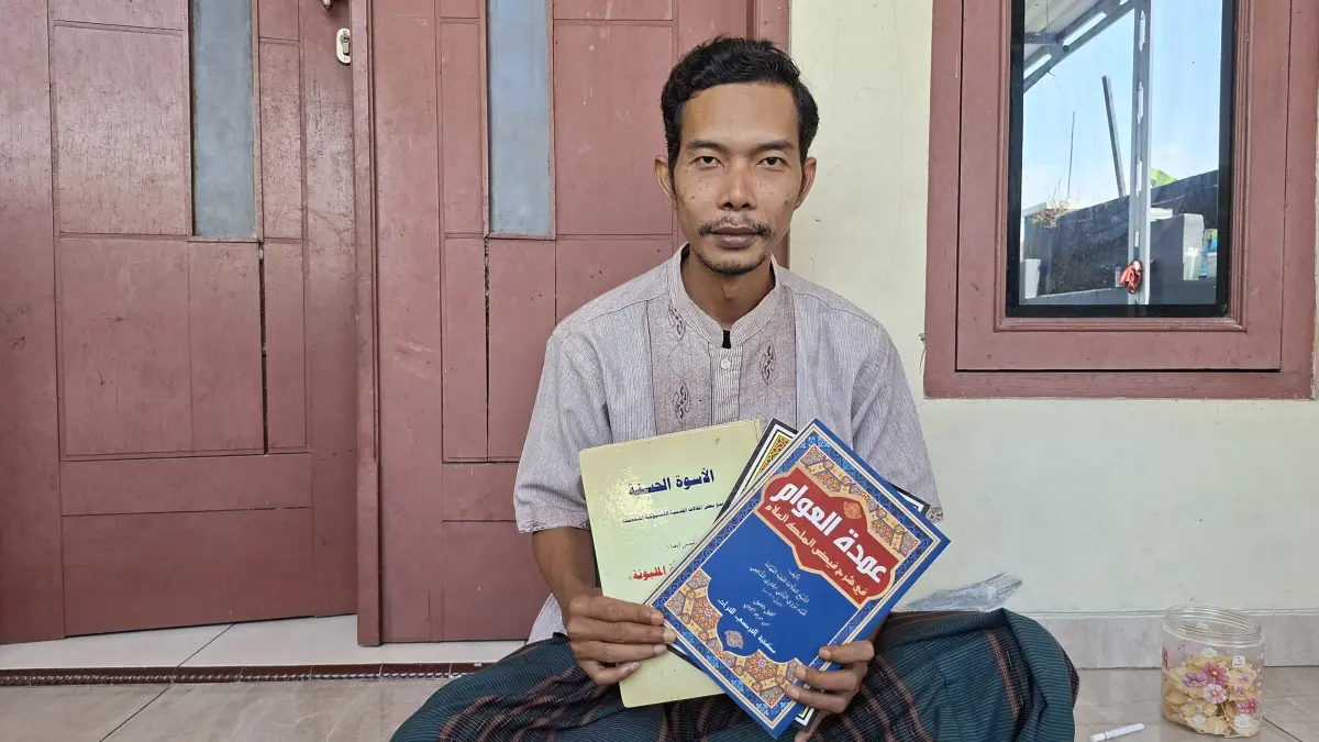 TUNJUKKAN: Mbah Riyan menunjukkan dan membacakan hasil karyanya yang berada di kediamannya, Senin (3/8). (ANDIKA TRISNA SAPUTRA/RADAR KUDUS)