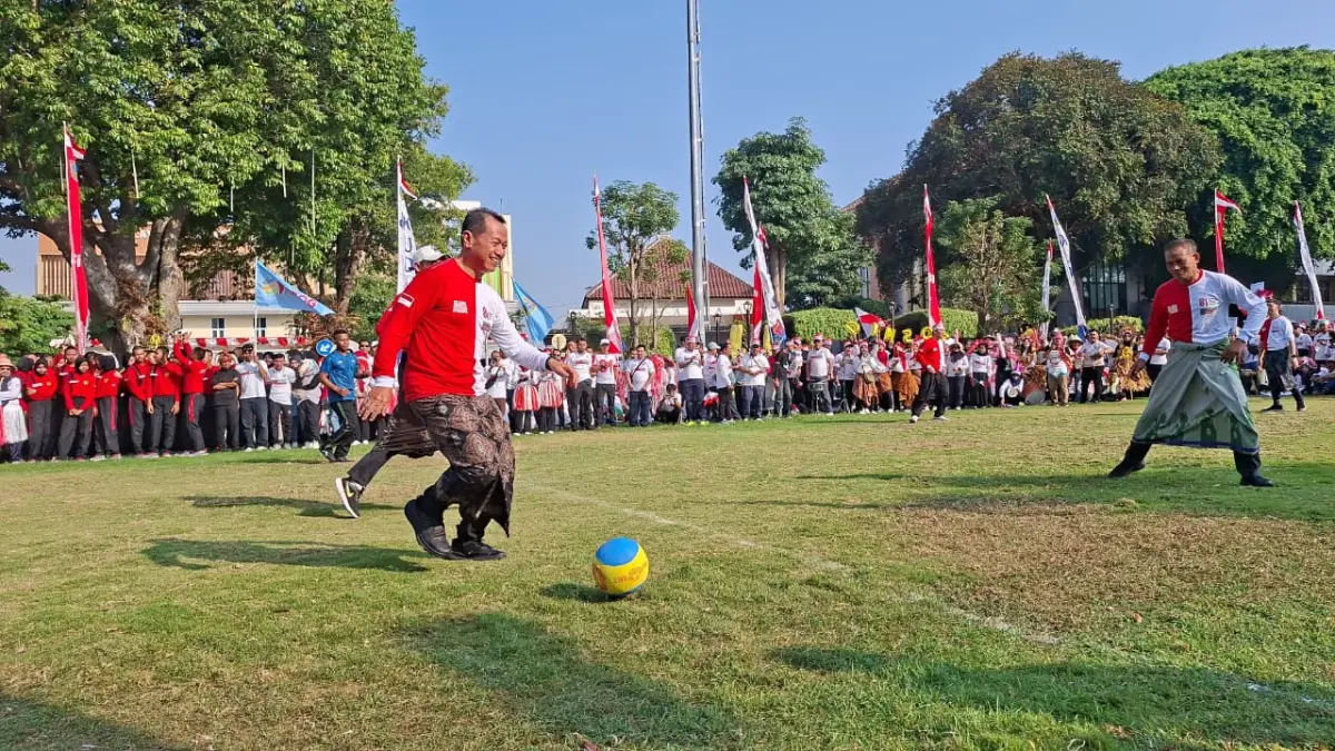 SERU: Bupati Kudus Sam’ani Intakoris menggiring bola di tengah lapangan melewati pemain lawan di halaman Pendapa Kabupaten Kudus, Jumat (7/8). (ANDIKA TRISNA SAPUTRA/RADAR KUDUS)