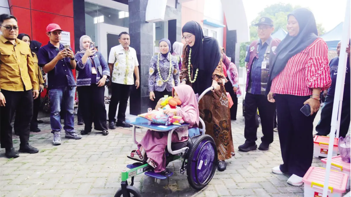 BERKUNJUNG: Ketua TP PKK Provinsi Jateng Nawal Arafah Yasin mendorong kursi roda anak yang mendapatkan bantuan didampingi Ketua TP PKK Kudus Endhah Endhayani di aula Kecamatan Kota, Kudus kemarin. (INDAH SUSANTI/RADAR KUDUS)