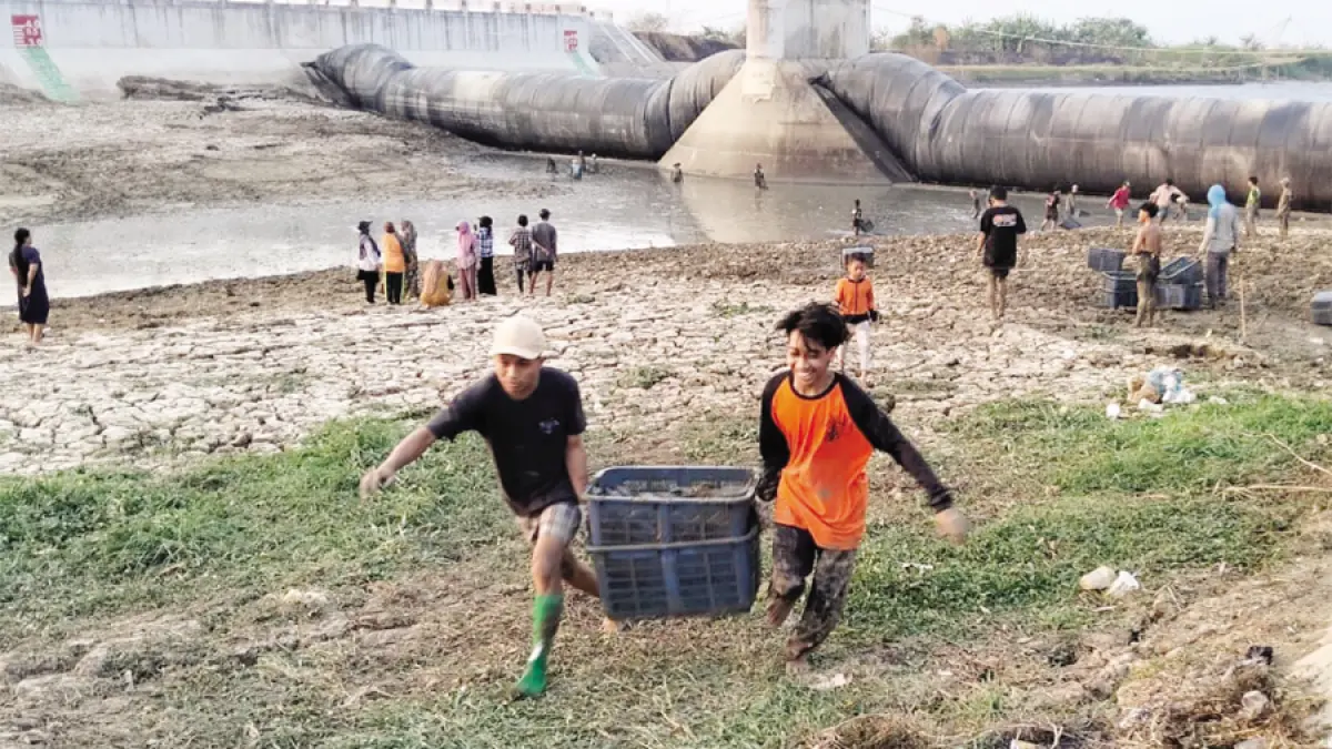 DIBAWA: Warga membawa basket berisi ikan sapu-sapu di Sungai Silugonggo kemarin. (ANDRE FAIDHIL FALAH/RADAR KUDUS)