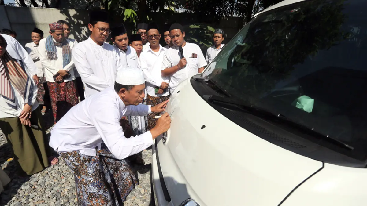 Direktur Jawa Pos Radar Kudus Baehaqi menandatangani kap mobil baru disaksikan para karyawan. (GALIH ERLAMBANG/RADAR KUDUS)