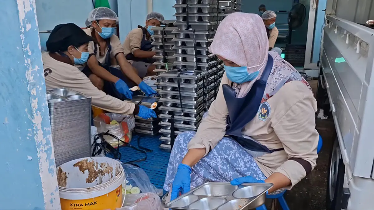 DIPEGANG: Pegawai SPPG membersihkan ompreng di dapur MBg. (ANDRE FAIDHIL FALAH/RADAR KUDUS)