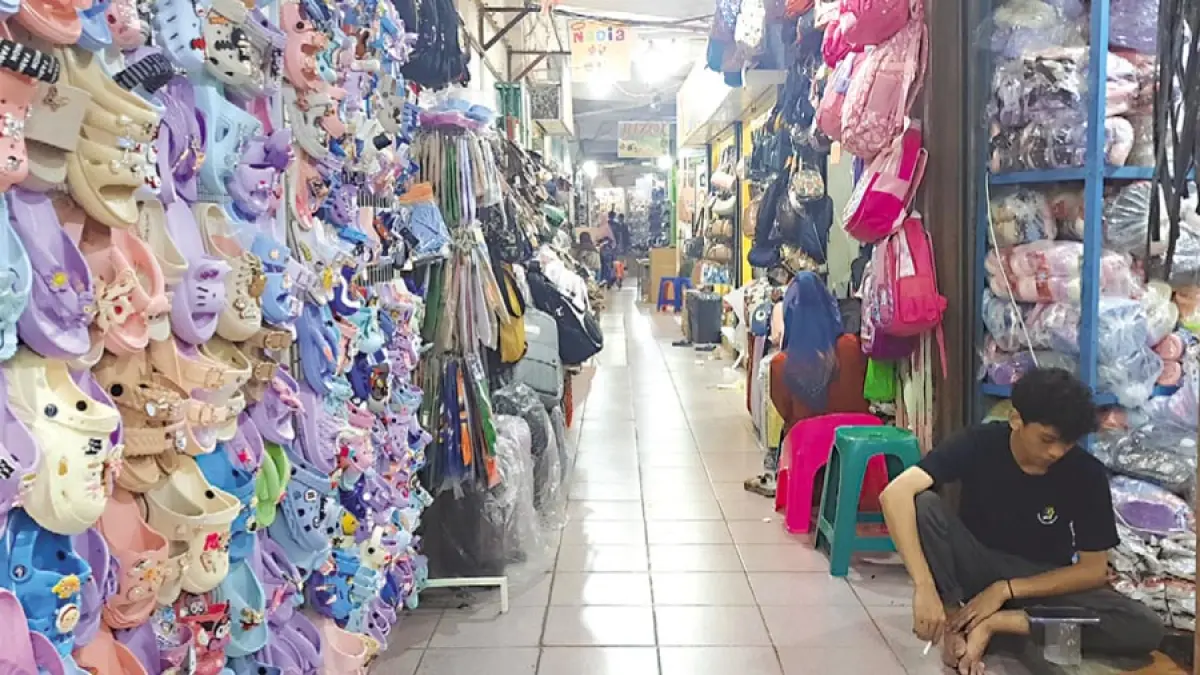 SEPI: Pedagang Pasar Kliwon Kudus duduk santai di depan dagangannya yang tak ada satu pun pembeli. (INDAH SUSANTI/RADAR KUDUS)