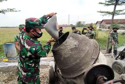SEMANGAT: Dandim 0719/Jepara Letkol Arh Tri Yudhi Herlambang ikut mengangkat pasir saat pengecoran jalan di Desa Ujungpandan, Welahan. (KODIM FOR RADAR KUDUS)