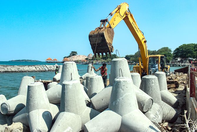 PROGRES: Pekerja menata tumpukan tetrapod untuk rehabilitasi water break di Pelabuhan Kartini menggunakan ekskavator kemarin. (MOH. NUR SYAHRI MUHARROM/RADAR KUDUS)