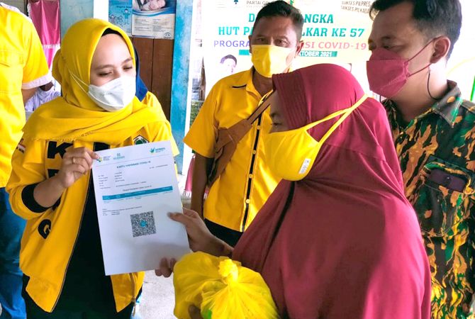 SERAHKAN SEMBAKO: Ketua KPPG Provinsi Jateng Padmasari Mestikajati didampingi Sekertaris DPD Golkar Bambang Widiastomo menyerahkan bantuan sembako kepada warga yang telah vaksin dalam rangka HUT ke-57 Golkar (SIROJUL MUNIR/RADAR KUDUS)