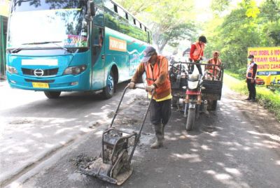 TAMBAL SULAM: Petugas dari Dinas PUPR menambal lubang di Jalan Desa Jatilor tembus Desa godong. (SIROJUL MUNIR/RADAR KUDUS)