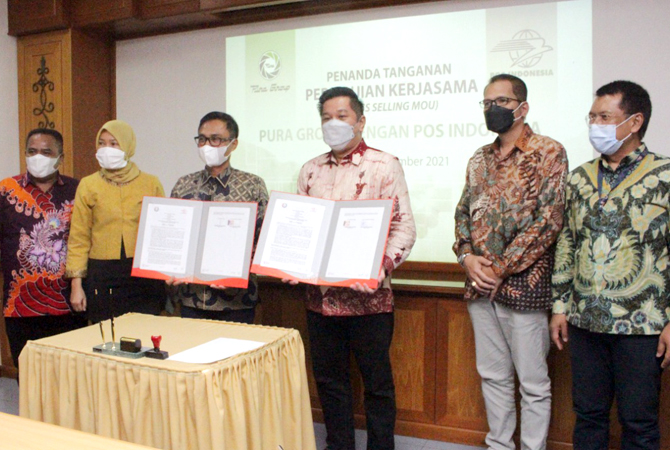 JALIN KERJA SAMA: Dirut PT Pos Indonesia (Persero) Faizal Rochmad Djoemadi dan Dirut Pura Group Johanes Slamet Harjanto menunjukkan MoU di kantor Pura Group (10/12) lalu. (PURA GROUP FOR RADAR KUDUS)