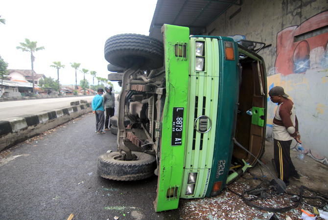SOPIR MENGANTUK TRUK TERGULING: Truk trailer dengan Nopol L 8873 AI bermuatan kayu yang akan dibawa ke Jepara terguling di Ngembal Kulon karena sopirnya mengantuk. (DONNY SETYAWAN/RADAR KUDUS)