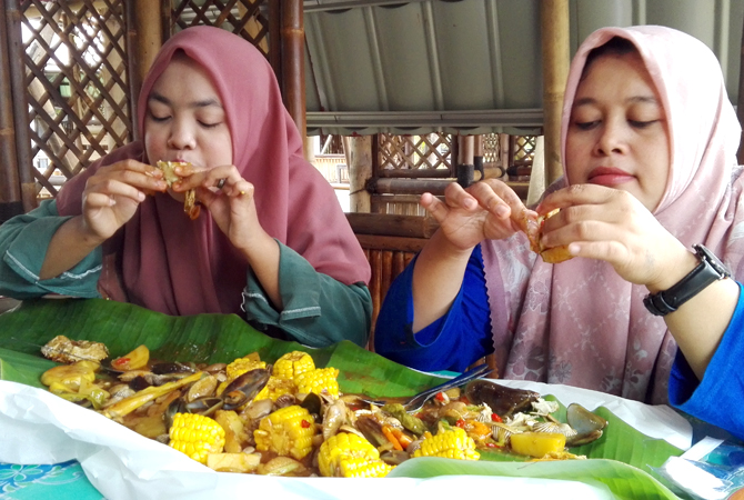 KERANG: Dua orang sedang menikmati olahan kerang mix seafood. (ARIKA KHORIYA/RADAR KUDUS)