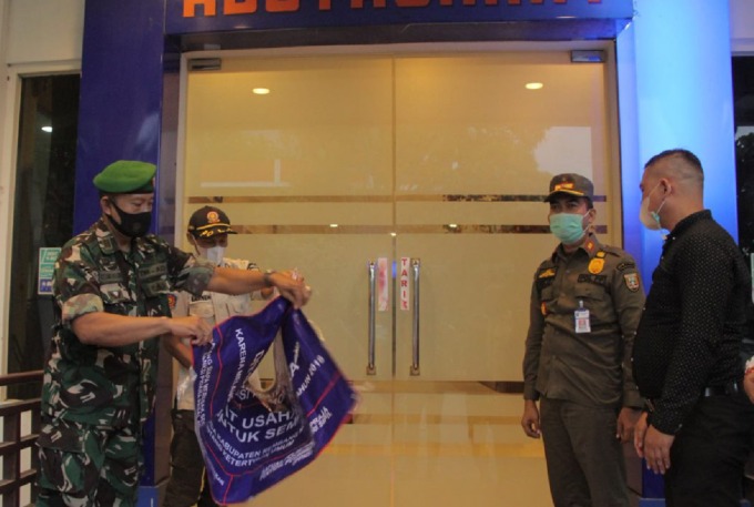 BERI KELONGGARAN: Satpol PP kabupaten Rembang didampingi TNI-Polri dan disaksikan manajemen Hotel Gajah Mada saat membuka segel pintu luar penginapan sebelah timur kemarin sore. (WISNU AJI/RADAR KUDUS)