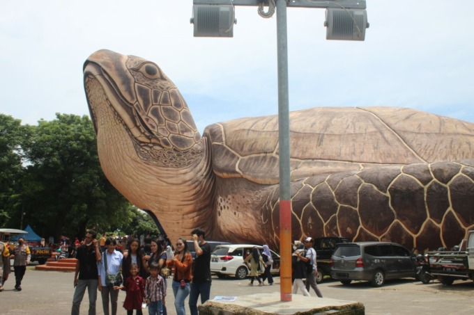 BERFOTO: Pengunjung bersama keluarga menggunakan jasa foto di depan patung kura-kura Ocean Park kemarin (01/01). (NIBROS HASSANI/RADAR KUDUS)