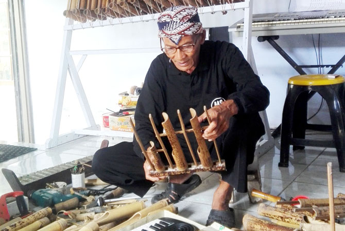 LESTARIKAN BUDAYA: Suparlan saat melakukan proses pembuatan angklung dikediamannya. (ARIKA KHOIRIYA/RADAR KUDUS)