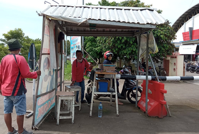 BEKERJA: Penjaga sedang berada di pos keamanan dan parkir Pasar Baru pada (17/11). (ARIKA KHOIRIYA/RADAR KUDUS)