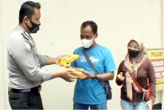DAPAT MINYAK GORENG: Anggota Polsek Gubug menyerahkan minyak goreng setelah vaksinasi pada Senin (28/2). (SIROJUL MUNIR/RADAR KUDUS)