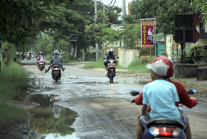 BANYAK KUBANGAN: Warga melintas di Jalan Slamet Riyadi yang rusak dan menjadi target perbaikan. (WISNU AJI/RADAR KUDUS)