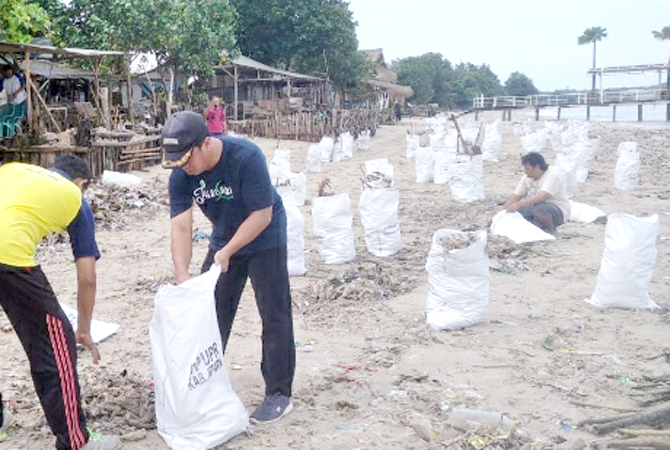 SEMANGAT: Agus Santoso didampingi perangkat lainnya saat membersihkan Pantai Tegalsambi dari sampah belum lama ini. (AGUS SANTOSO FOR RADAR KUDUS)