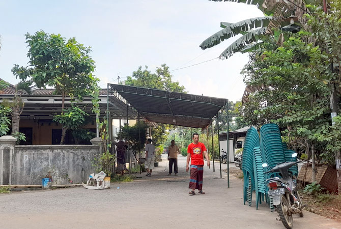 MELINTAS: Seorang warga Desa Bandungrejo, Kalinyamatan melewati tenda duka yang dipasang sore kemarin di depan rumah salah satu korban tewas kecelakaan di Pemalang. (NIBROS HASSANI/RADAR KUDUS)