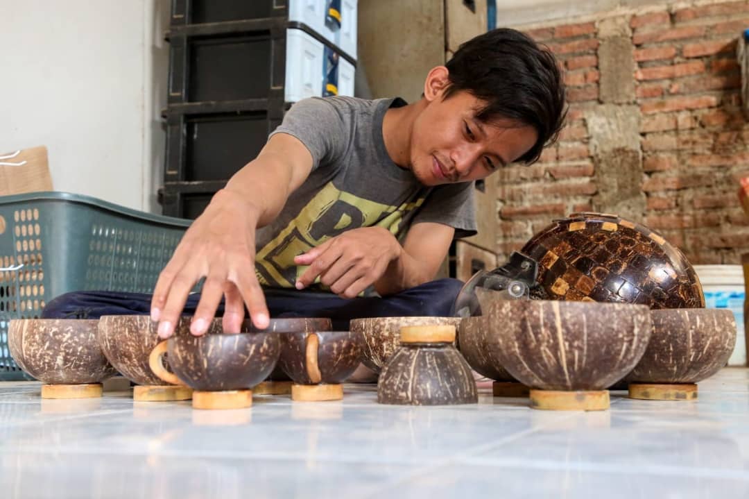 KREATIF: Tiar Bachroni menata gelas yang dibuat dari batok kelapa. (DONNY SETYAWAN/RADAR KUDUS)