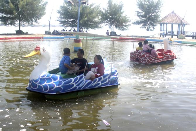 BERMAIN: Wisatawan mencoba wahana perahu bebek di Taman Kartini. (DOK. RADAR KUDUS)