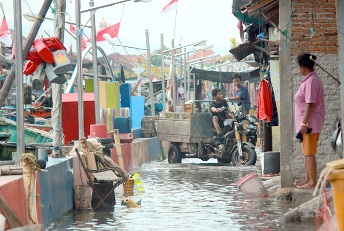 KEMBALI NAIK: Warga menerobos genangan air rob yang menggenang di jalanan Kelurahan Jobokuto, Jepara kemarin. (MOH. NUR SYAHRI MUHARROM/RADAR KUDUS)