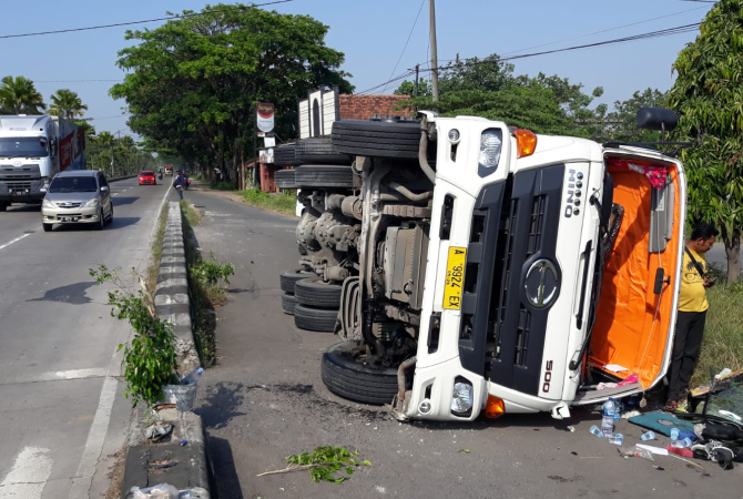 TERGULING: Truk terguling ke badan jalan setelah menghindari motor di jalan Lingkar  Timur turut Desa Megawon. (GALIH ERLAMBANG W/ RADAR KUDUS)