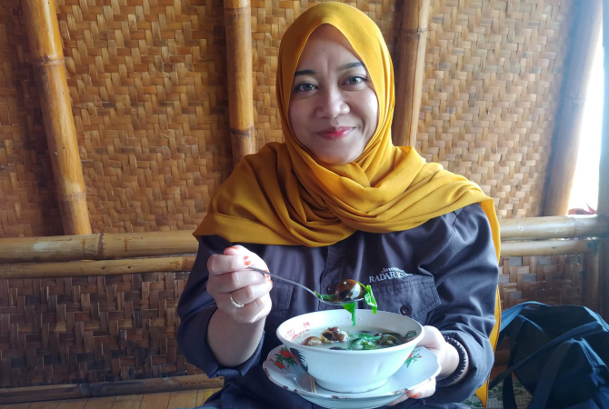 MENIKMATI: Noor Syafaatul Udhma, wartawan Radar Kudus menikmati hidangan sayur keong srutup daun singkil. (KHOLID HAZMI/RADAR KUDUS)