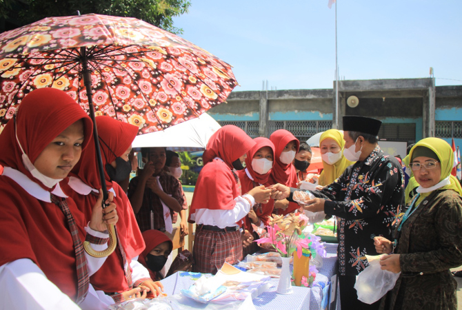NGELARISI: Pengawas Pembina SMPN 3 Rembang dari Dinas Pendidikan, Pemuda dan Olahraga (Dindipora), Kabupaten Rembang Slamet Prayitno, Kepala SMPN 3 Rembang Menik Mustikatun ikut ngelarisi produk hasil kreasi siswa di bazar kewirausahaan, Rabu (24/8). (WIS