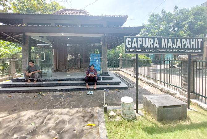 BERSEJARAH: Warga tampak bersantai di depan bangunan yang digunakan untuk menyimpan Gerbang Majapahit. (ANDRE FAIDHIL FALAH/RADAR KUDUS)