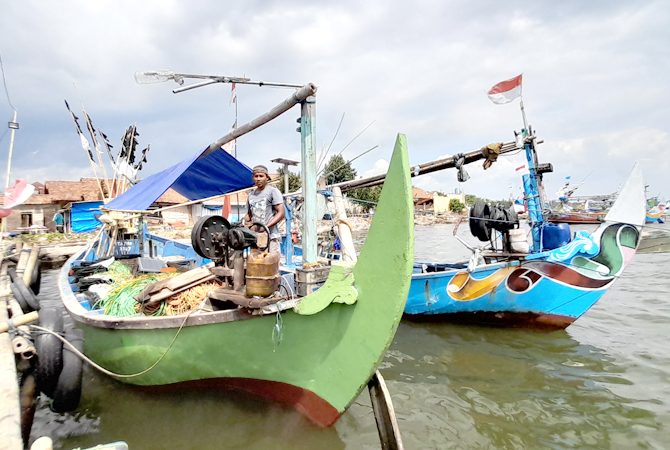 PERSIAPAN: Nelayan Demaan, Jepara, memperbaiki mesin kapal di pelabuhan setempat kemarin. (NIBROS HASSANI/JAWA POS RADAR KUDUS)