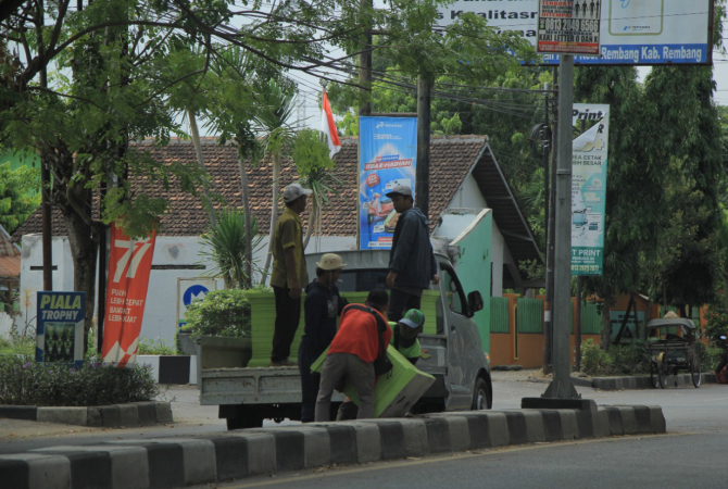 ERJA KERAS: Pekerja dari DLH Kabupaten Rembang harus kerja keras mengangkut puluhan pot yang ditaruh di median Jalan Pemuda, Kamis lalu (6/10). (WISNU AJI/RADAR KUDUS)