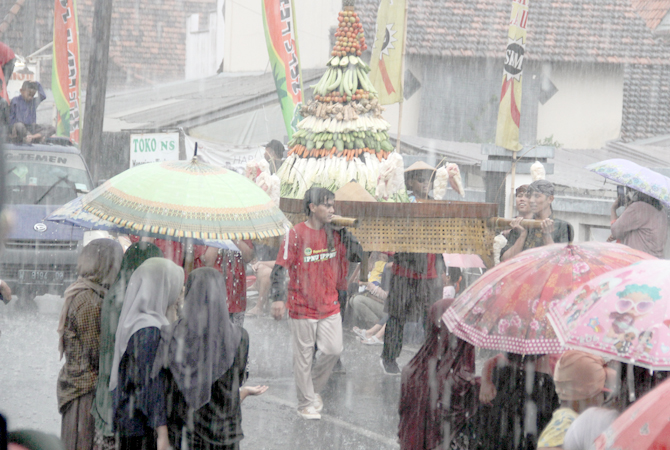 TETAP JALAN: Warga menyaksikan kirab ampyang maulid di Desa Loram Kulon, Jati, Kudus, yang berlangsung meriah kemarin. Dalam acara itu sempat turun hujan es kemarin sore. (GALIH ERLAMBANG W/ RADAR KUDUS)
