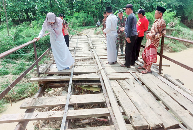 MEMPRIHATINKAN: Warga Desa Deras, Kedungjati melihat kerusakan di jembatan penghubung Desa Deras-Padas. (HASAN ASARI FOR RADAR KUDUS)