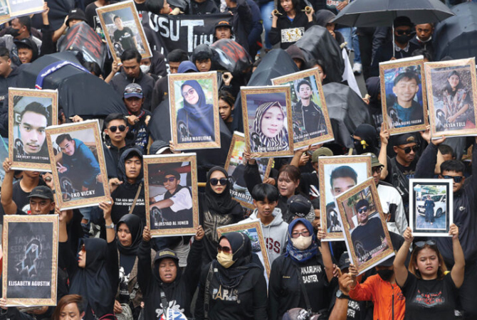 TIGA TUNTUTAN: Foto-foto korban dibawa dalam aksi menuntut pengusutan tuntas tragedi Kanjuruhan di Malang kemarin (10/11). (ROBERTUS RISKY/JAWA POS)